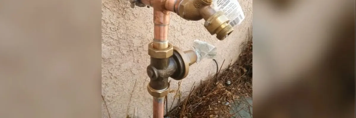 Wide view of outdoor hose bib connection being repaired near the wall for Hose Bib Repair Replacement service in Mechanicsburg