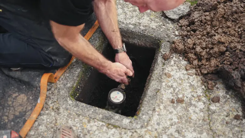 Close view of open sewer lateral repair with pipe exposed in the ground for Spring Sewer Backup Prevention