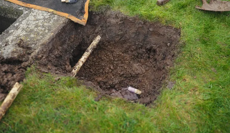 Open sewer lateral repair with pipe exposed in the ground for Root Intrusion and Your Sewer Line